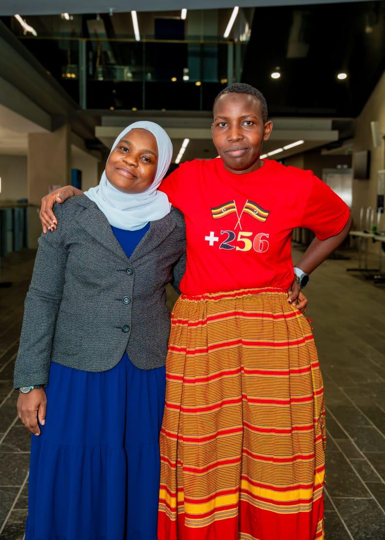 Two members smiling together in Ugandan colours