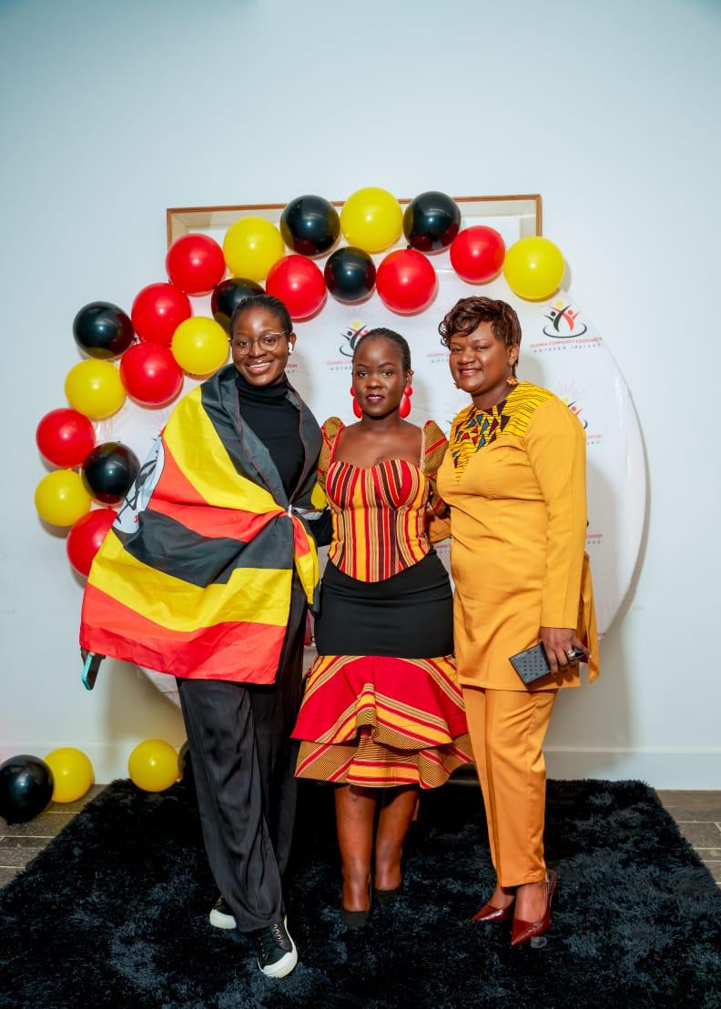 Three members posing together with a Uganda flag